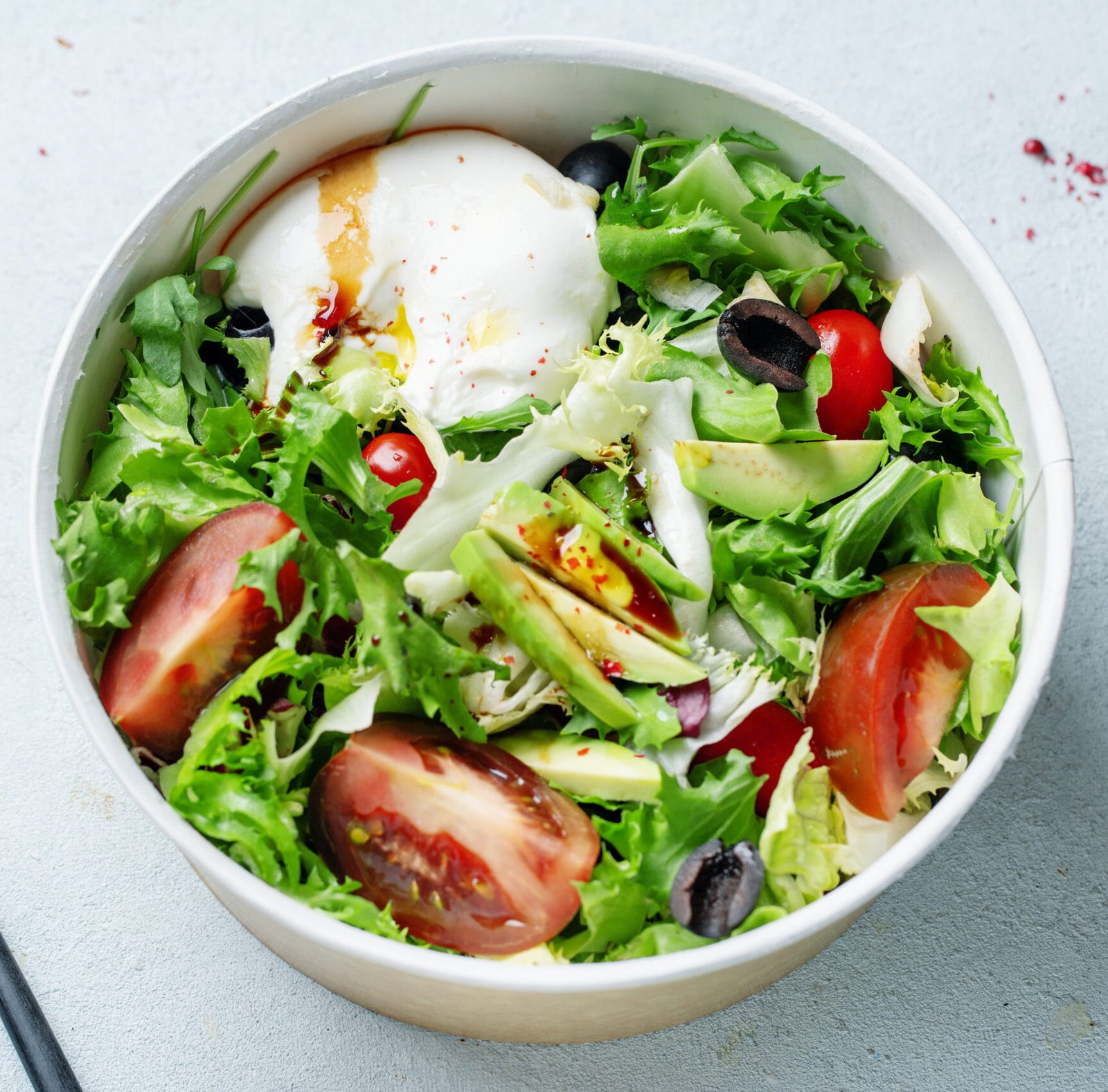 Tasty salad with mozzarella tomatoes avocado served in bowl.